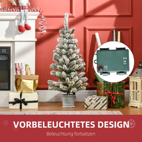 Künstlicher Weihnachtsbaum mit Schneeeffekt und LED-Beleuchtung im Topf, Batteriefach mit Schalter im Detail, festlich dekoriert neben Kamin.