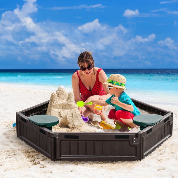 Mutter und Kind spielen mit einer Sandkiste am Strand und bauen eine Sandburg