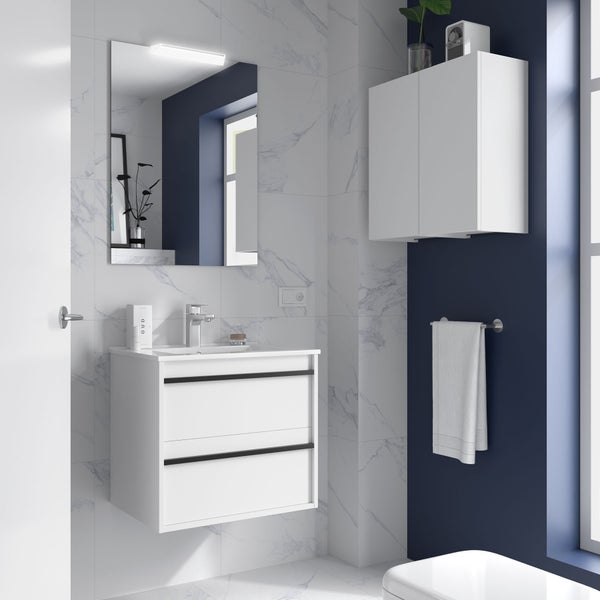 Modernes Badezimmer mit weißem Waschtischunterschrank, beleuchtetem Spiegel und Hängeschrank vor hellen Marmoroptik-Fliesen und blauer Wand.