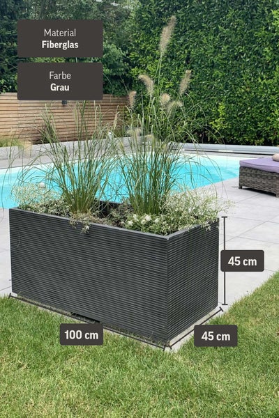 Grauer Pflanztrog aus Fiberglas mit Rillenstruktur, Maße 100 mal 45 mal 45 Zentimeter, bepflanzt im Garten am Pool.