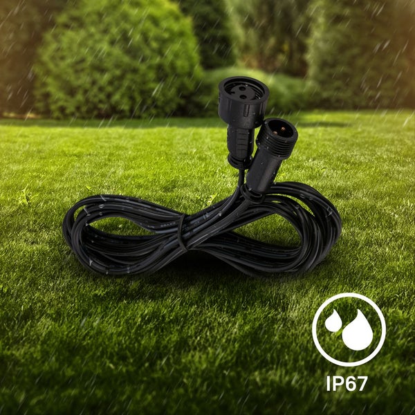 Schwarzes wasserfestes Verlängerungskabel mit IP67 Schutzklasse auf einer Rasenfläche im Regen liegend.