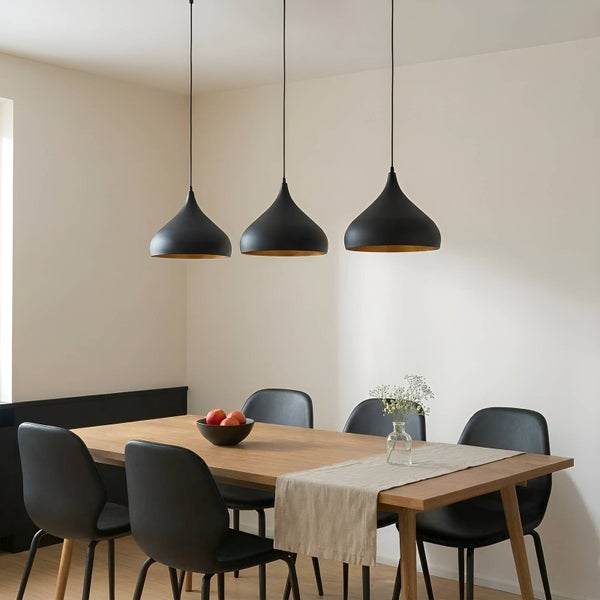 Esszimmer mit Holztisch, Stühlen und drei schwarzen Hängelampen.