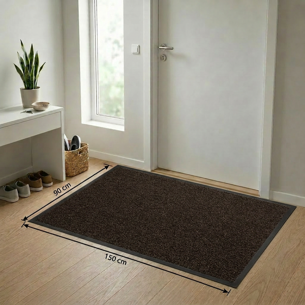 Dunkelbraune Schmutzfangmatte mit schwarzem Rand, 90 mal 150 Zentimeter, vor einer weißen Tür im hellen Eingangsbereich mit Holzfußboden.