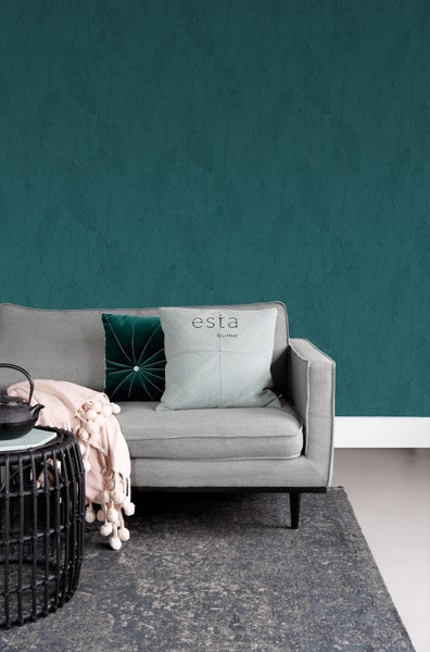 Wohnzimmer mit grauer Couch, Kissen, Teppich und dunkelgrüner Tapete mit Blattmuster
