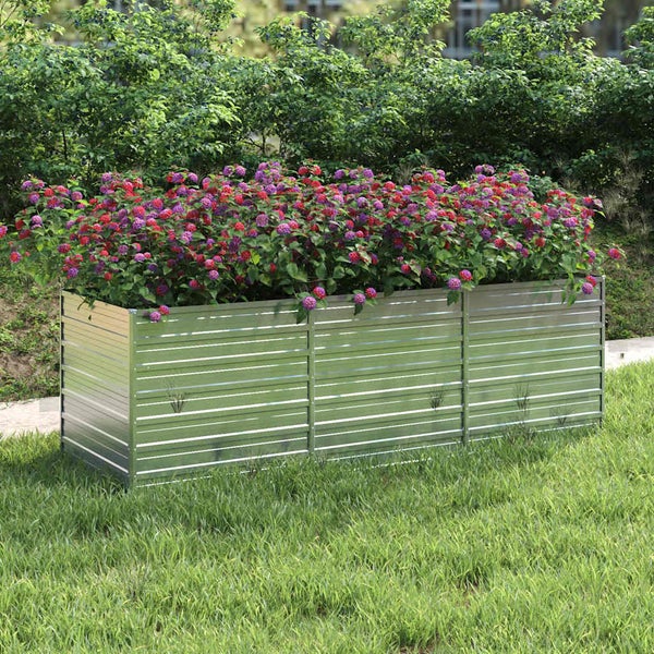 Rechteckiges Hochbeet aus Metall in einem Garten mit blühenden Pflanzen.