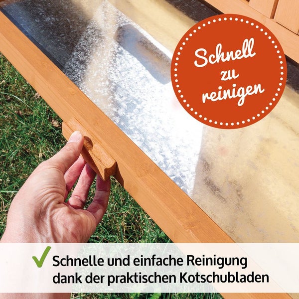 Eine Hand zieht die verzinkte Kotschublade aus einem Kleintierstall aus Holz zur einfachen Reinigung heraus.