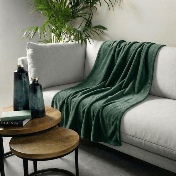 Wohnzimmer-Szene mit Couch, grüner Kuscheldecke und Beistelltisch