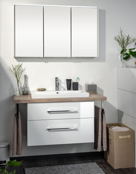 Badezimmer mit Waschbeckenunterschrank, Waschtisch, Spiegelschrank und Accessoires für ein helles und organisiertes Ambiente.