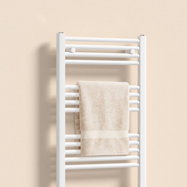 Weißer Badheizkörper in Leiterform mit beige Handtuch an der Wand montiert.