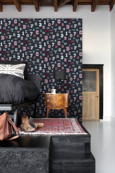 Schlafzimmer mit Bett, Nachttisch, Teppich und Tapete mit Buchstaben- und Zahlenmuster