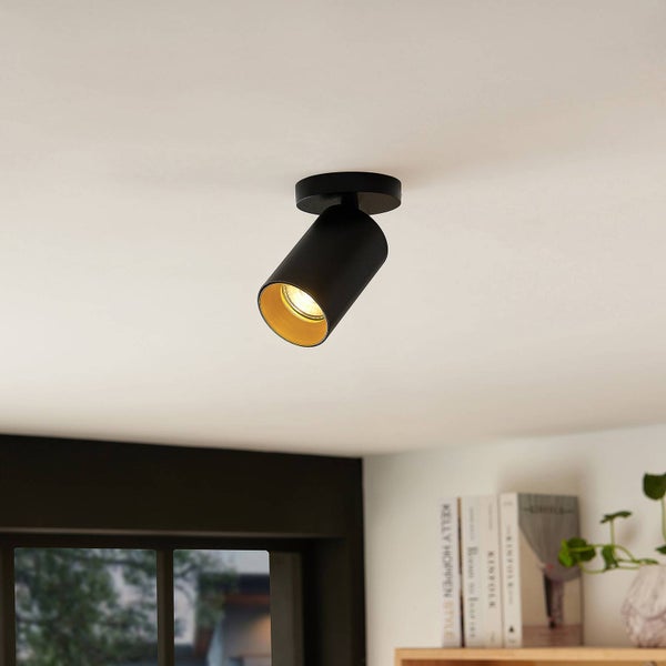 Schwarzer Deckenstrahler mit Leuchtmittel an der Decke montiert