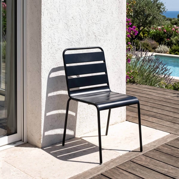 Moderner Gartenstuhl aus Metall mit Querstreben an Rückenlehne und Sitzfläche auf einer Terrasse neben einem Pool.