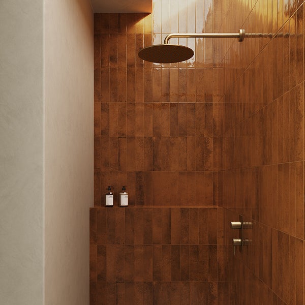 Moderne Dusche mit braunen Wandfliesen in Klinkeroptik, einer runden Kopfbrause in Messing und einer integrierten Ablagefläche.