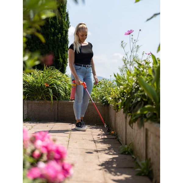 Frau entfernt Unkraut mit einem Gasbrenner im Garten