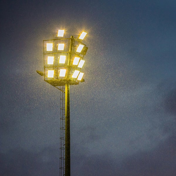 Beleuchteter Flutlichtstrahler mit Leiter im Regen