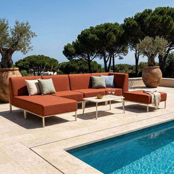 Moderne, helle Garten-Lounge-Gruppe mit modularem Sofa, Hocker und Tisch auf einer Steinterrasse am Pool.
