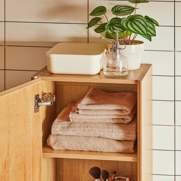 Badezimmeransicht mit offenem Holzschrank, Handtüchern und Dekoration