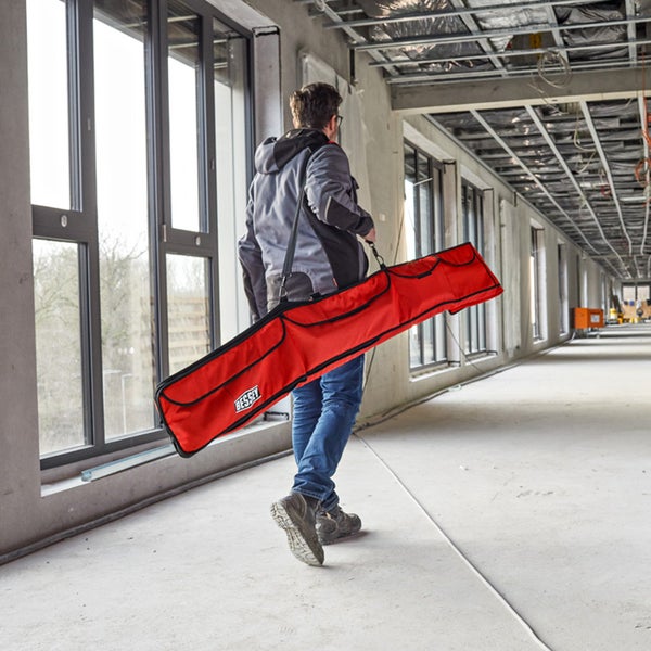 Ein Mann trägt eine rote Bessey Werkzeugtasche in einem unfertigen Gebäude.