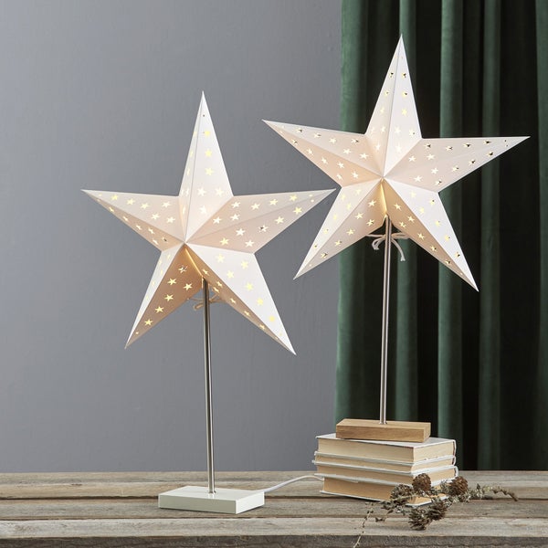 Zwei leuchtende Papiersterne auf Ständern als Dekoration auf einem Tisch