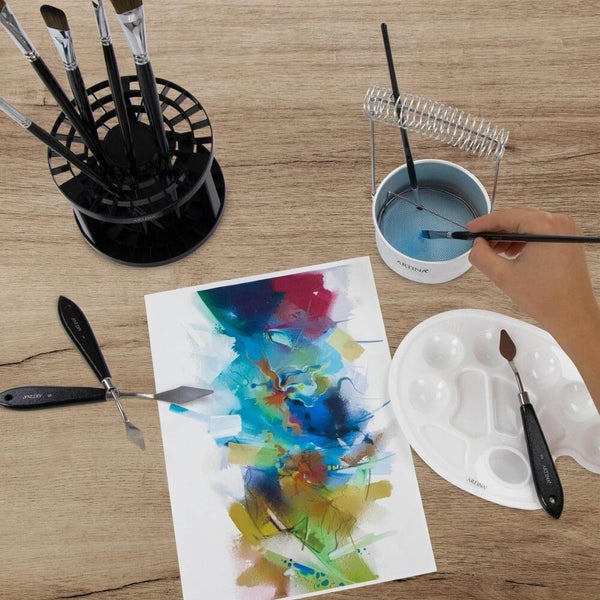 Kunstmalzubehör Set mit Pinseln, Spachteln, Reinigungsbehälter und Mischpalette auf einem Holztisch, Draufsicht.