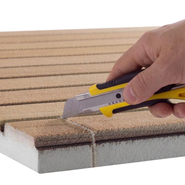 Hand schneidet Fassadendämmplatte mit einem Teppichmesser