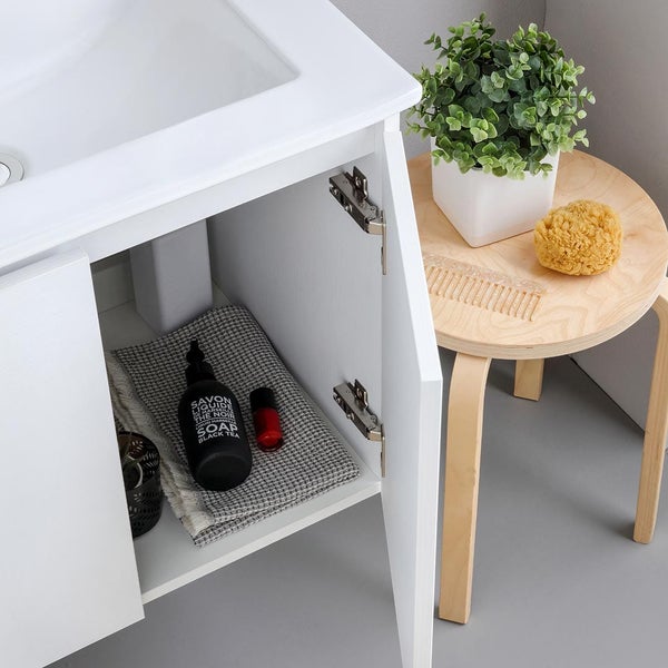 Badezimmer mit Waschbeckenunterschrank, Hocker, Pflanze, Schwamm und Badutensilien