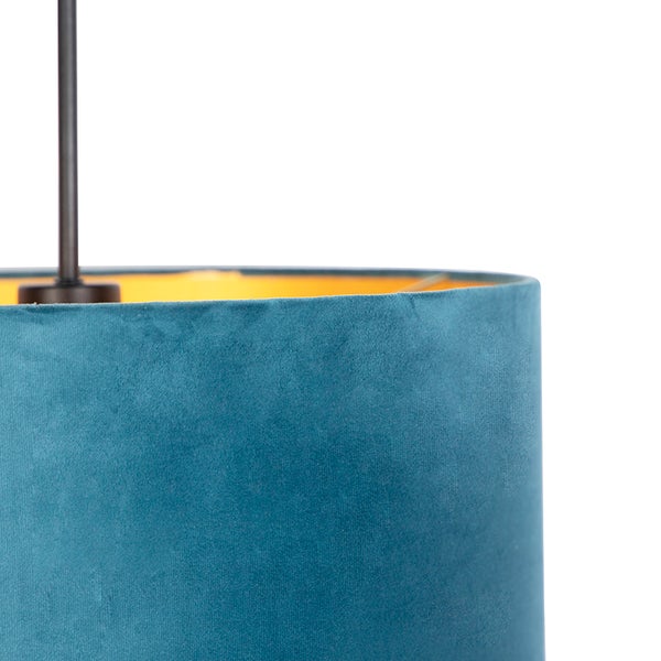 Nahaufnahme eines blauen Samtlampenschirms mit goldener Innenseite und dunkler Metallaufhängung.