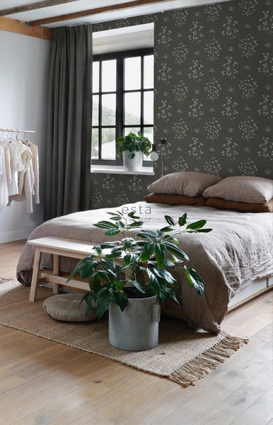 Schlafzimmer mit Bett, Fenster, Tapete mit Blumenmuster und Zimmerpflanzen.