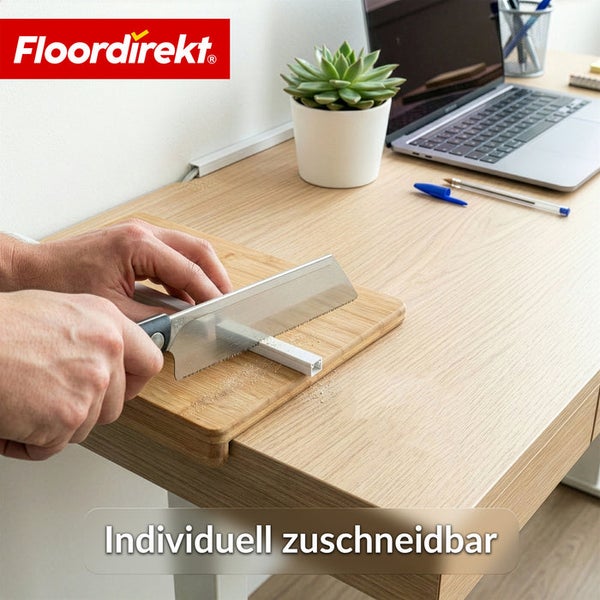 Eine Person schneidet einen Kunststoff-Kabelkanal mit einer Handsäge auf einem Holztisch zu. Floordirekt Logo. Aufgeräumter Arbeitsplatz.