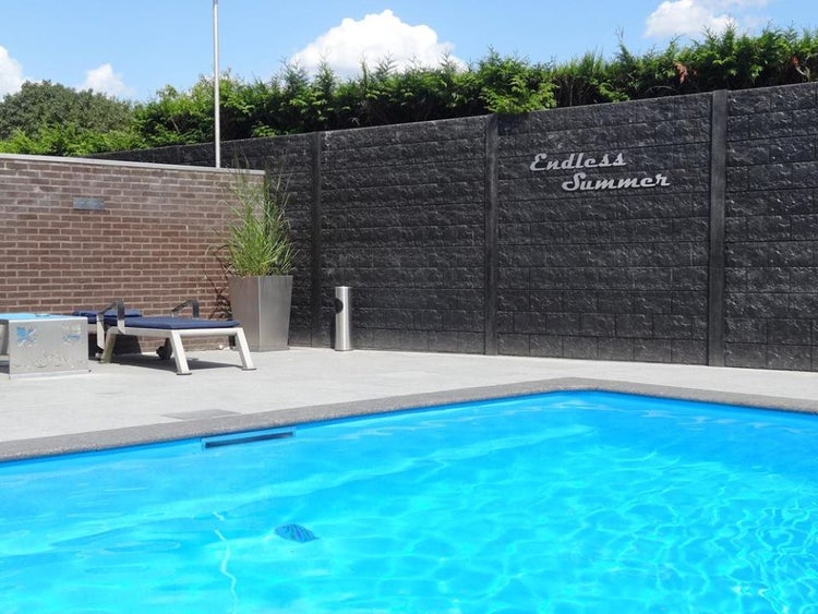 Swimmingpool mit Steinmauer und Gartenmöbeln