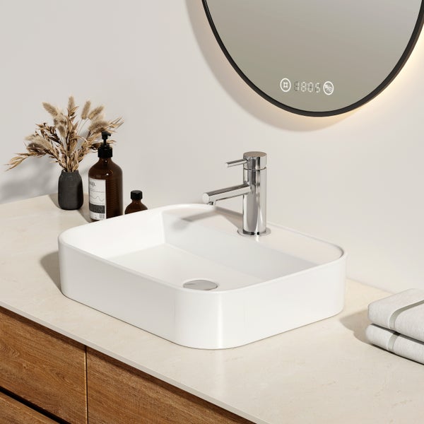 Modernes Badezimmer mit rechteckigem Aufsatzwaschbecken aus weißer Keramik, Chrom-Armatur, hellem Waschtisch aus Holz und rundem Spiegel.