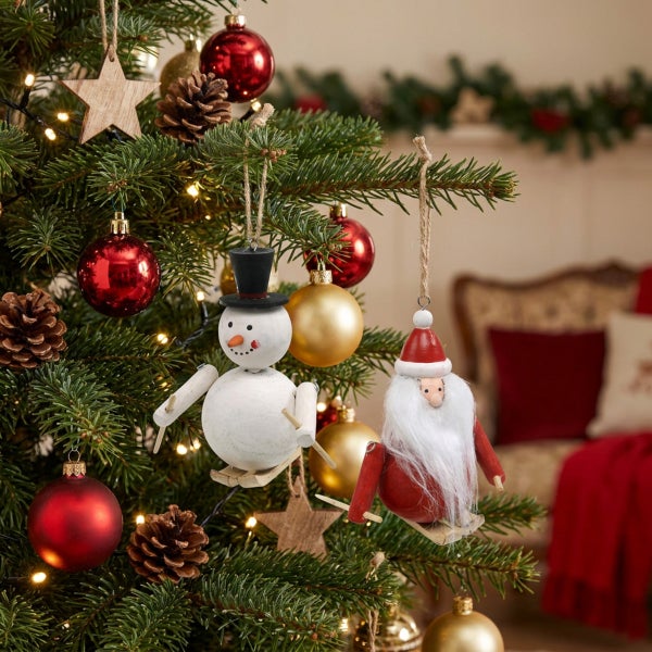 Weihnachtsbaum geschmückt mit Holzfiguren in Form eines Schneemanns und Weihnachtsmanns auf Skiern sowie Kugeln, Sternen und Tannenzapfen.