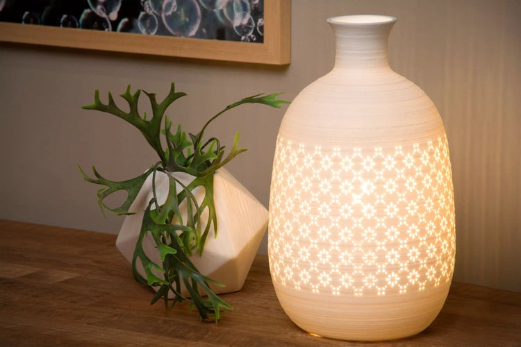 Dekorative Lampe mit Muster und Zimmerpflanze auf einem Tisch