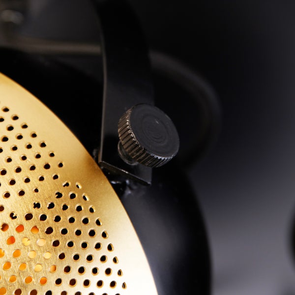 Detailaufnahme einer Lampe mit verstellbarem Knopf und einem Lampenschirm mit Lochmuster.