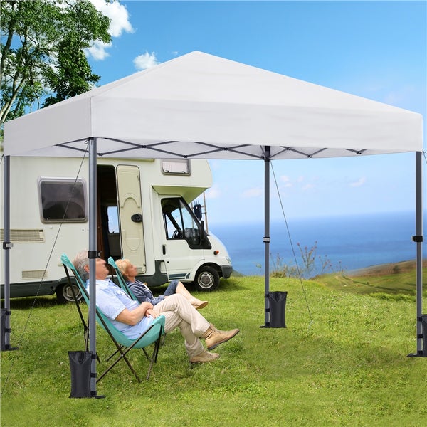 Personen sitzen unter einem Pavillon neben einem Wohnmobil im Freien.