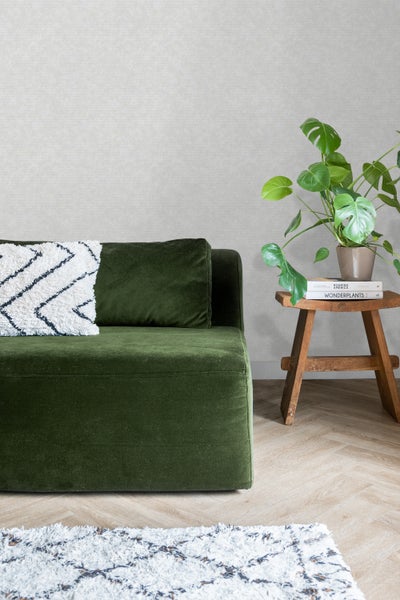 Gemütliche Sitzecke mit grüner Couch, Zierkissen, kleinem Holztisch und Zimmerpflanze