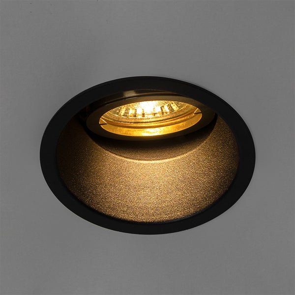 Runder Einbaustrahler in Schwarz mit goldfarbener Innenseite und eingeschaltetem warmweißem Licht.