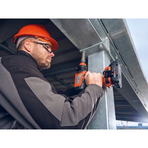 Handwerker mit Schutzhelm und Brille verwendet einen Akku Schlagschrauber für die Montage an einer Metallkonstruktion.