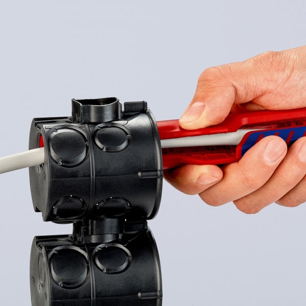 Installateur führt eine elektrische Leitung in eine Gerätedose ein.