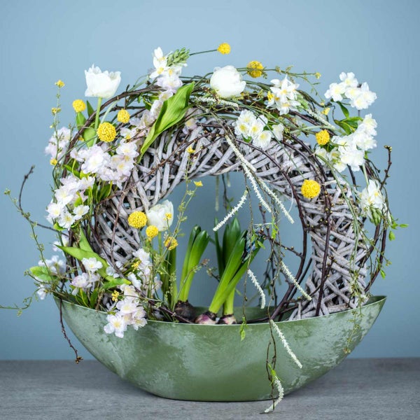 Blumenarrangement mit Weidenkranz, Tulpen, Hyazinthen und Zierblüten in einer Schale