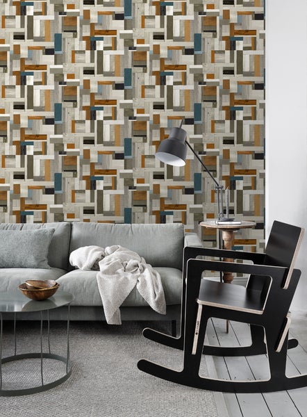 Wohnzimmer mit grauer Couch, Lampe und gemusterter Tapete in Holzoptik
