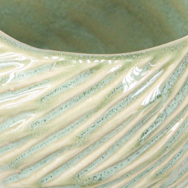 Nahaufnahme eines hellgrünen Keramiktopfes mit glasierter Oberfläche und diagonaler Rillenstruktur.