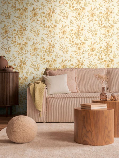 Wohnraum mit Vliestapete mit floralem Blumenmuster an der Wand und einem modernen Sofa mit Kissen.