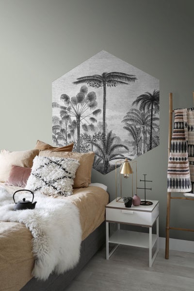 Schlafzimmer mit Wanddekoration im Dschungelstil, Nachttisch und Textilien