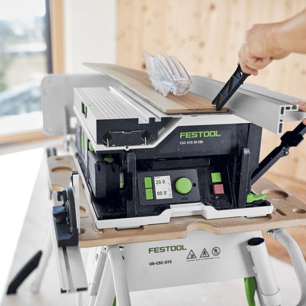 Festool Tischkreissäge CSC SYS 50 EBI auf einem Arbeitstisch mit einer Person, die ein Holzstück schiebt
