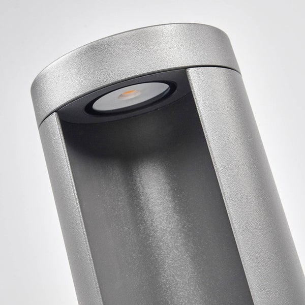 Nahaufnahme einer zylindrischen LED-Außenleuchte aus grauem Metall mit nach unten strahlendem Licht.