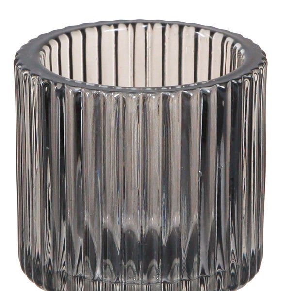 Geriffelter Teelichthalter aus grauem Glas in zylindrischer Form.