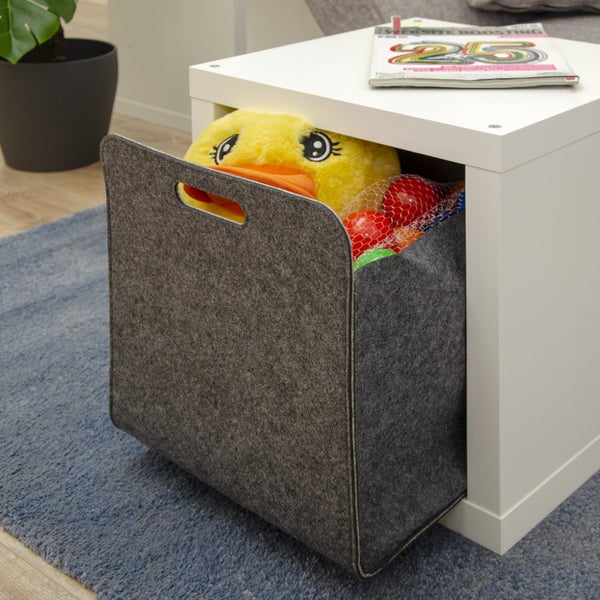 Grauer Filzkorb als Aufbewahrungsbox in einem weißen Regal mit Spielzeug gefüllt.