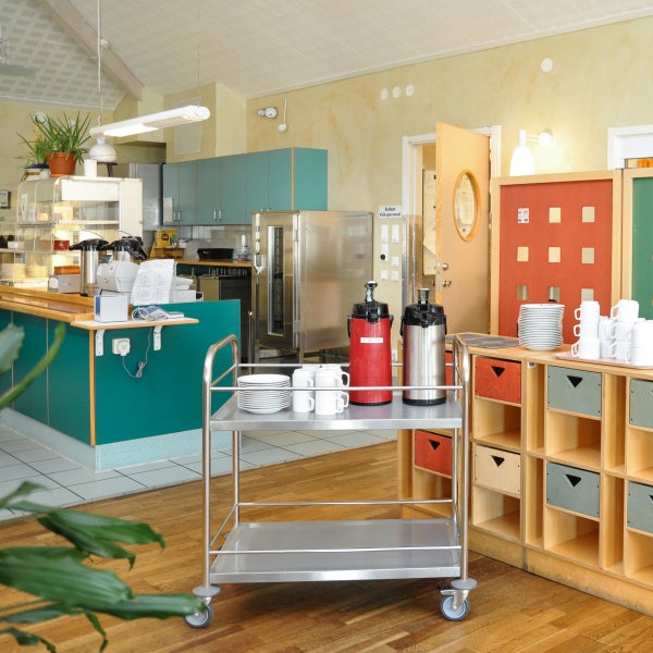 Kantinenbereich mit Servierwagen, Geschirr und Warmhaltebehältern in einer hellen Umgebung