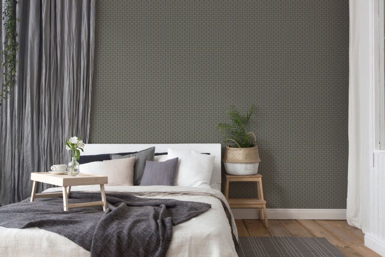 Schlafzimmer mit Bett, Nachttisch und geometrischer Tapete